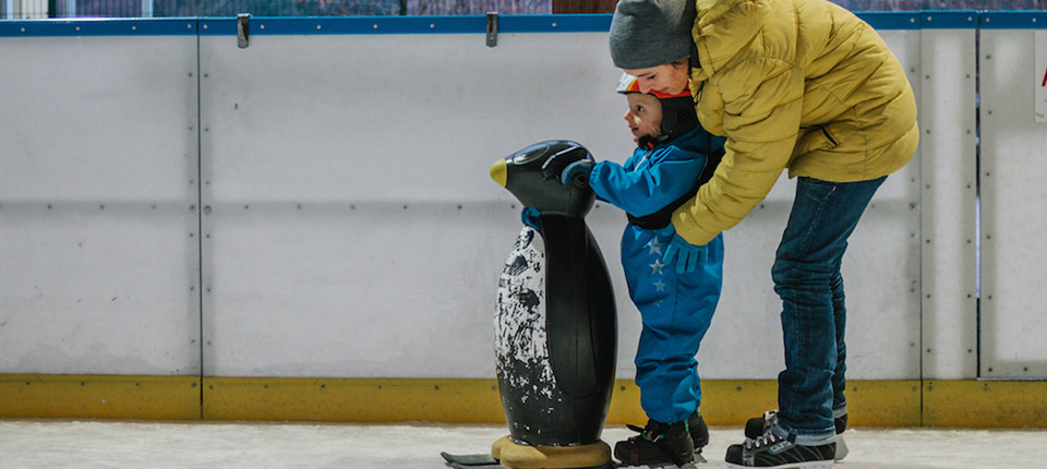 mother is showing her son how to skate on ice