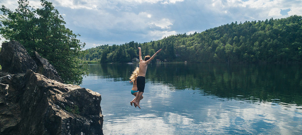 Young couple jumping into a lake